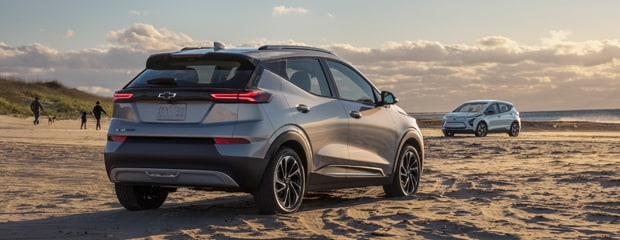 Rear view of a dark gray 2024 Chevrolet Equinox EV driving on sand area