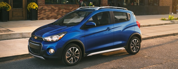 A blue Chevrolet Spark hatchback parked on the road.