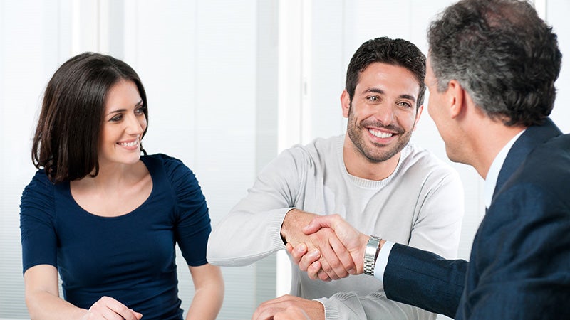 Two people sitting at a desk while another person